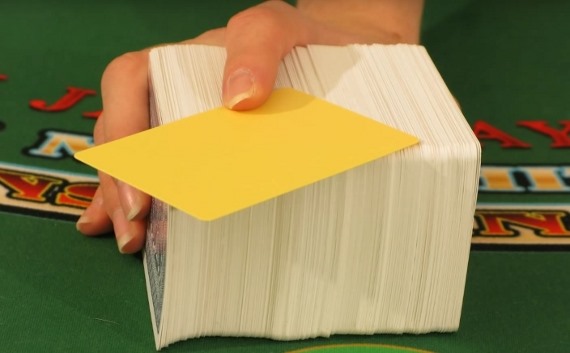 The dealer is offering the player the yellow cut card Подрезная карта в блэкджеке
