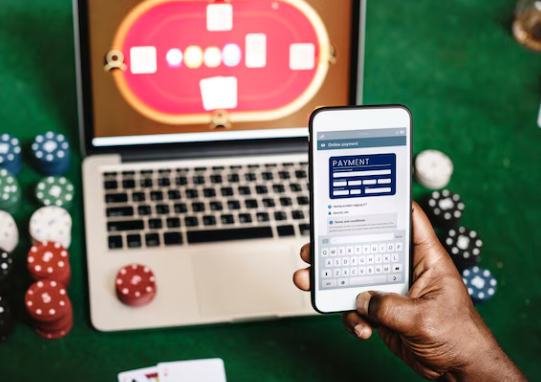 laptop with casino chips around it while person holds phone
