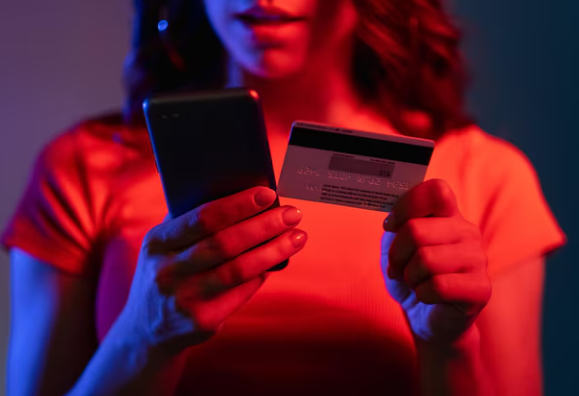 woman looking at phone with credit card in her hand