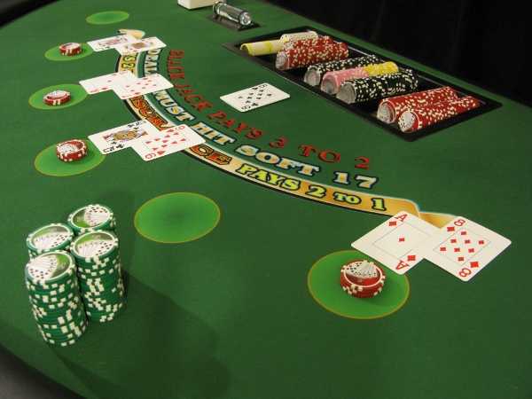 A large stack of green chips on the player's side of blackjack