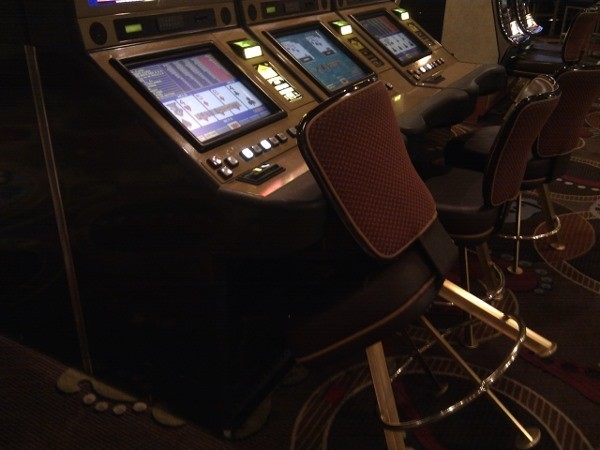 The slot machine has money in it and the chair is tilted forward The slot machine has money in it and the chair is tilted forward