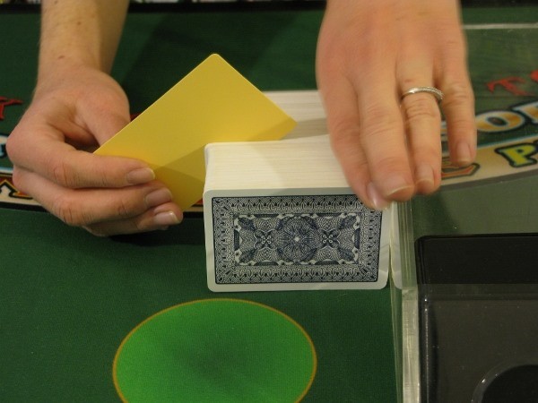 The dealer is putting a yellow cut card in a deck of 8 The dealer is putting a yellow cut card in a deck of 8