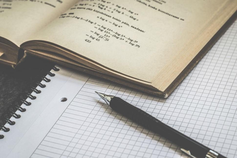 A math book with paper and a pen