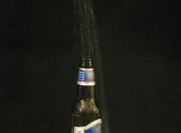 A beer bottle with liquid pouring in it A beer bottle with liquid pouring in it