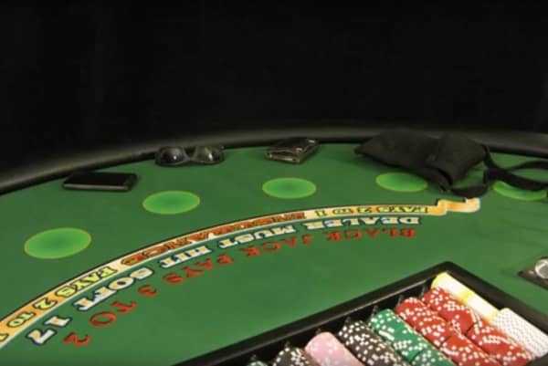 The blackjack table has sunglasses, a purse, a wallet and a phone on it