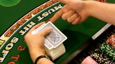 The dealer positions the edge against their other hand The dealer positions the edge against their other hand